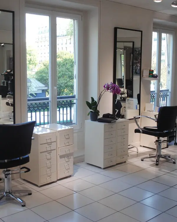 Salon lumineux avec fauteuils noirs et grands miroirs