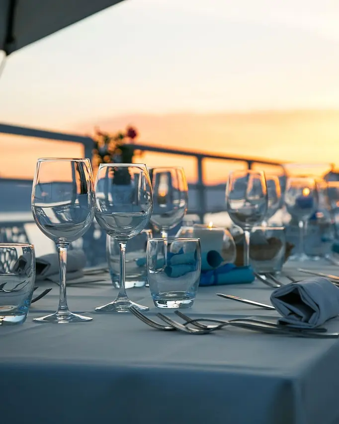 Table dressée en terrasse face à la mer au coucher du soleil