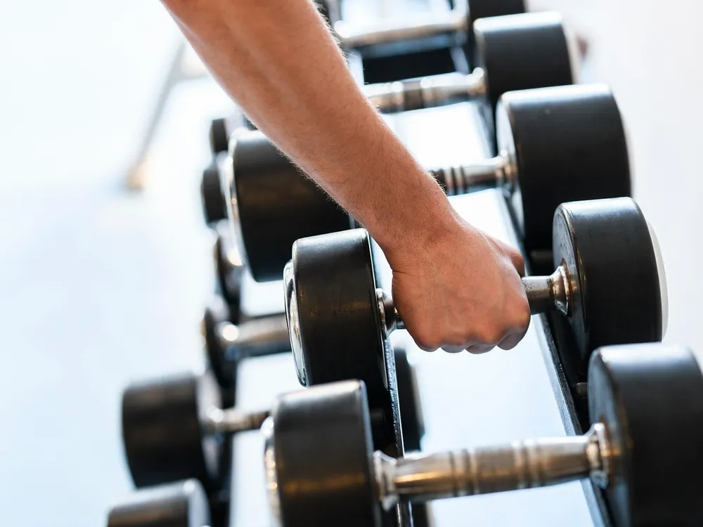 Une main qui prend un haltère sur le rack